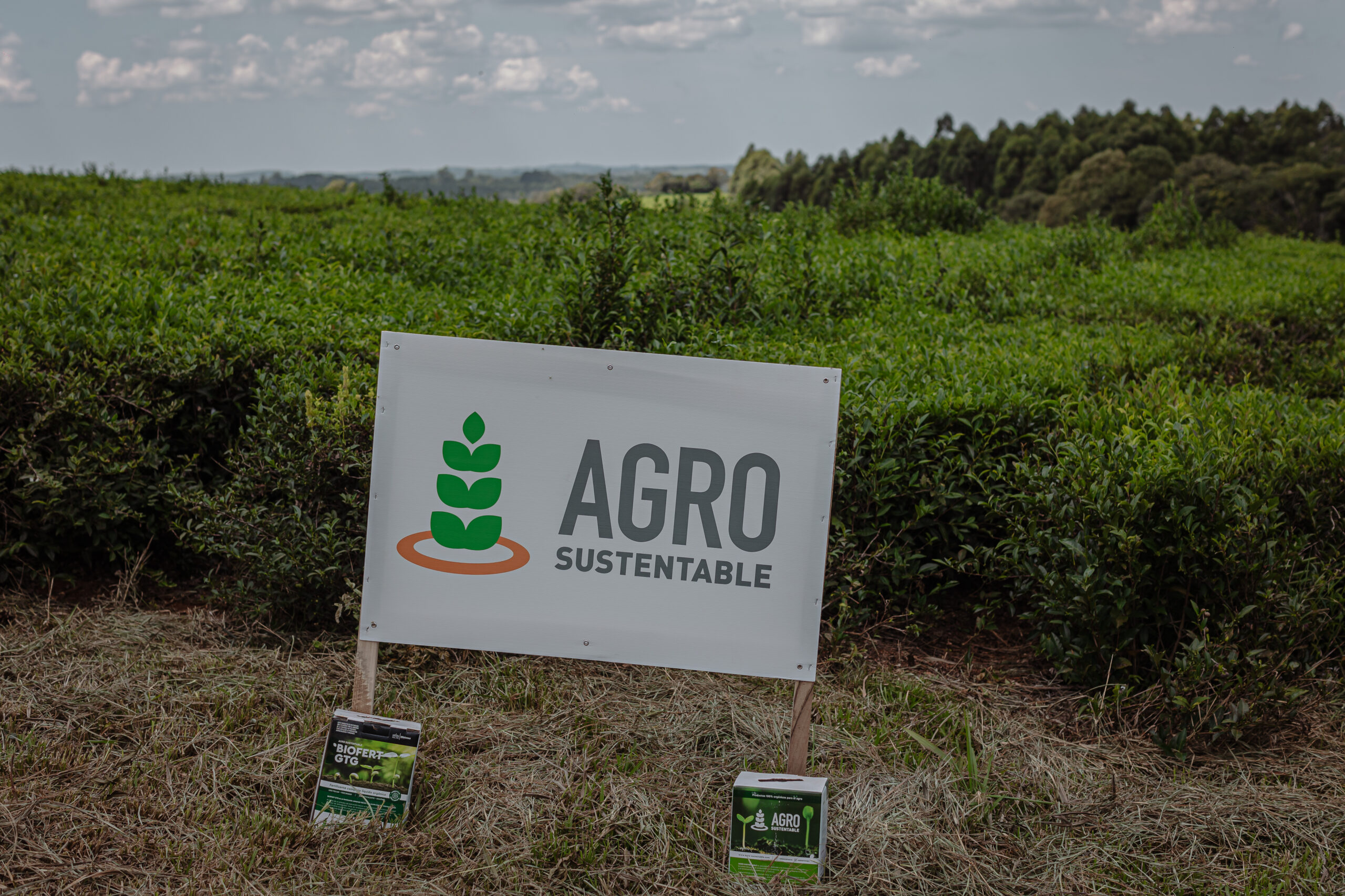 Cartel de Agro Sustentable junto a bioinsumos en un campo verde.