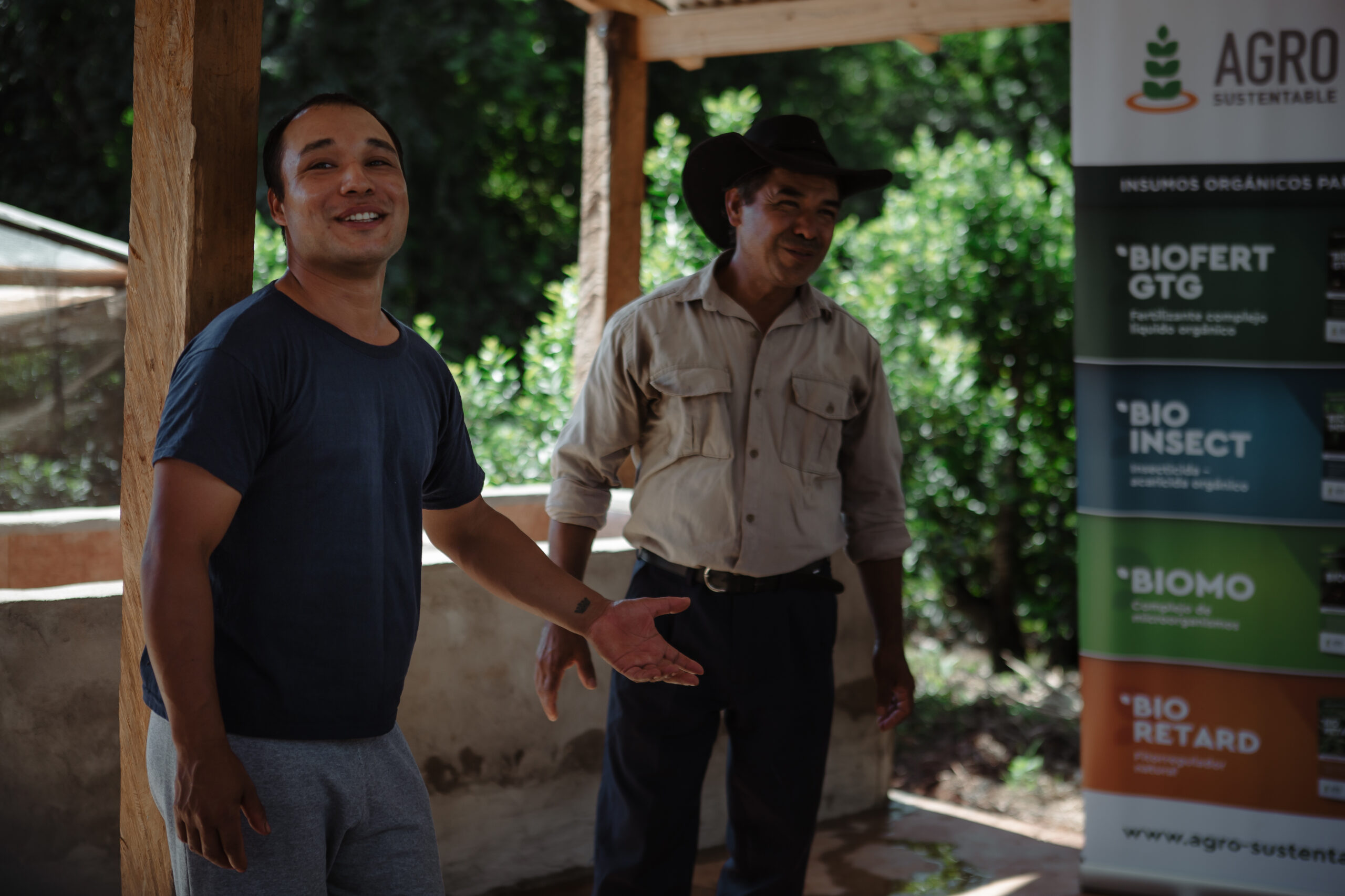 Dos productores conversan frente a un cartel de Agro Sustentable con insumos tecnológicos para cultivos.
